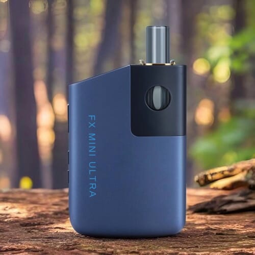 The Wolkenkraft FX Mini Ultra vaporizer in blue colour standing on a piece of wood in a forest